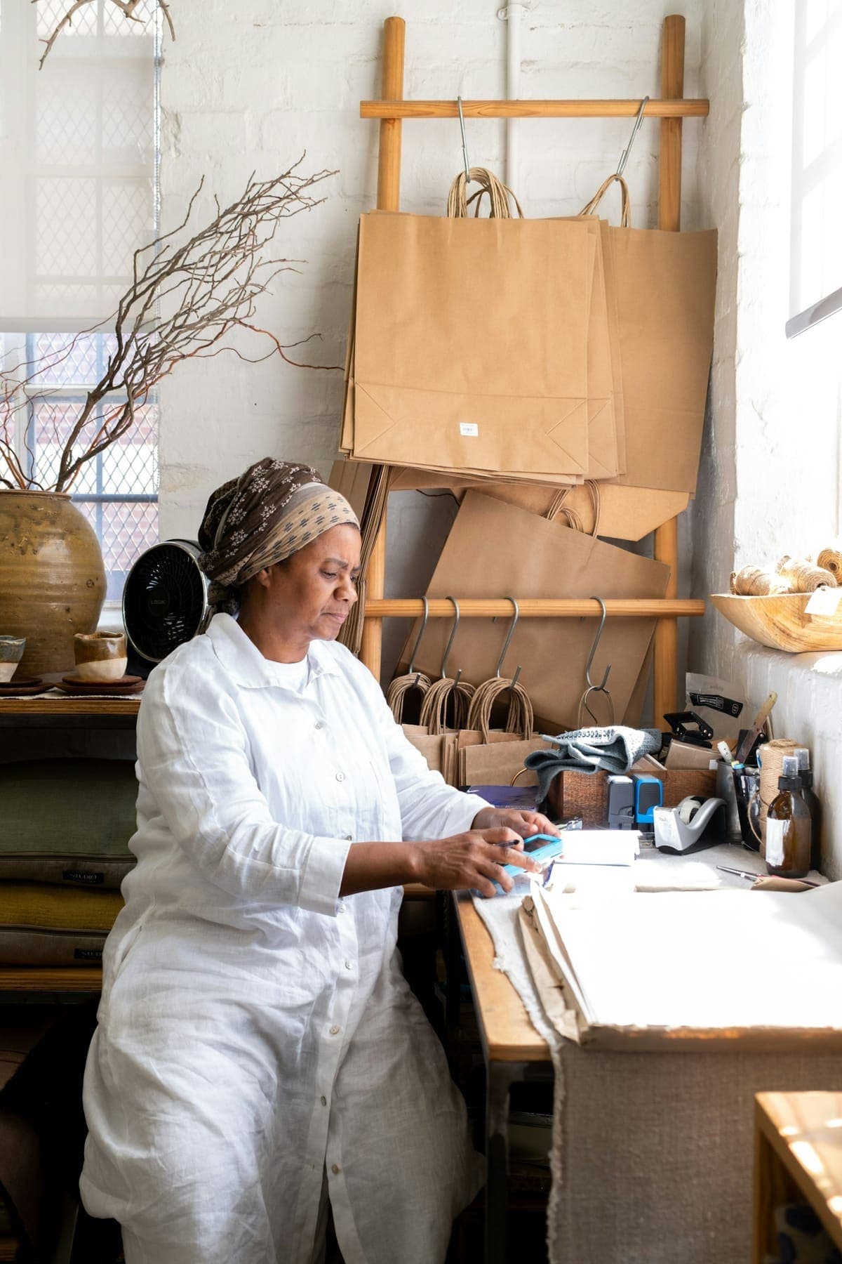 A maker wraps an order at a workbench lined with paper bags