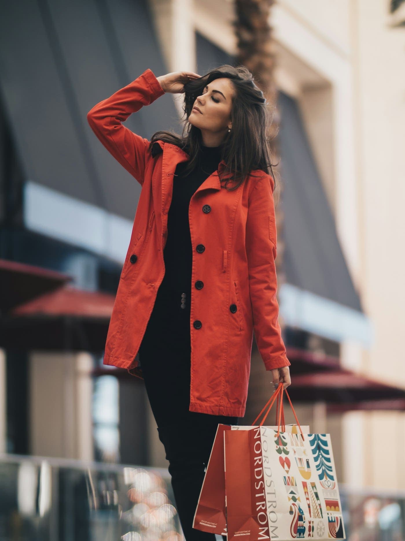 A woman in a red coat walking past a shop window